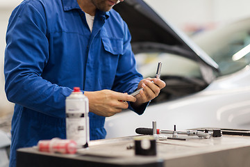 Image showing mechanic man with wrench repairing car at workshop