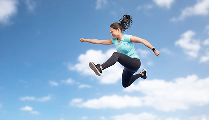 Image showing happy smiling sporty young woman jumping in sky