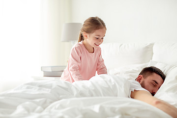 Image showing little girl waking her sleeping father up in bed