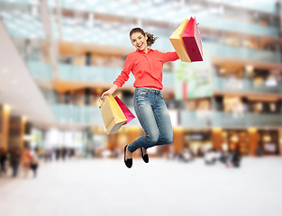 Image showing smiling young woman with shopping bags jumping