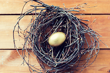 Image showing close up of golden easter egg in nest on wood