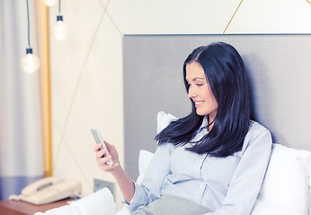 Image showing happy businesswoman with smartphone in hotel room