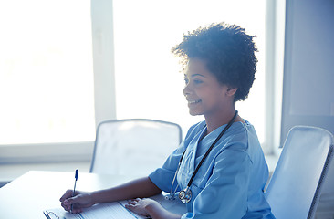 Image showing happy female doctor or nurse writing at hospital