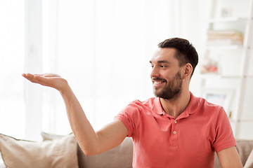 Image showing happy man holding something imaginary at home