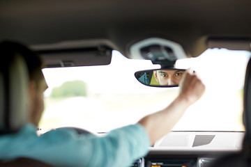 Image showing man driving car adjusting rearview mirror