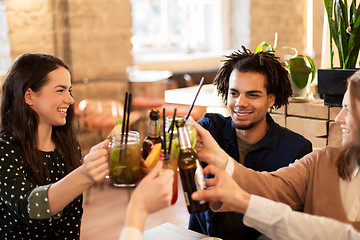 Image showing happy friends clinking drinks at bar or cafe