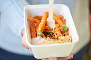 Image showing close up of hand holding plate with sweet potato