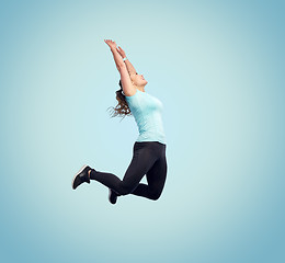 Image showing happy smiling sporty young woman jumping in air