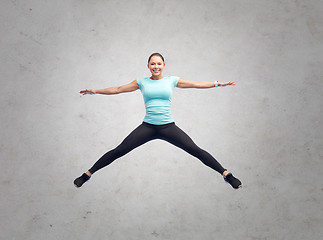 Image showing happy smiling sporty young woman jumping in air