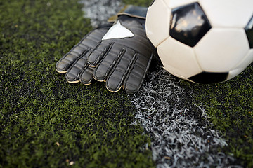 Image showing soccer ball and goalkeeper gloves on field