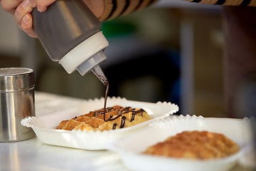 Image showing close up of cook adding syrop to waffle