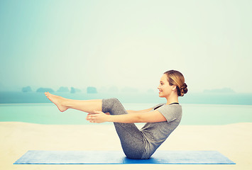 Image showing woman making yoga in half-boat pose on mat