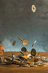 Image showing The silver and golden coins and falling coins on wooden background