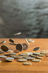 Image showing The silver and golden coins and falling coins on wooden background