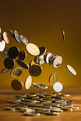 Image showing The silver and golden coins and falling coins on wooden background