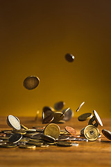 Image showing The silver and golden coins and falling coins on wooden background