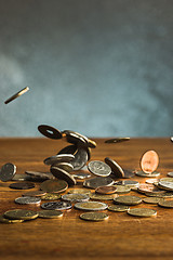 Image showing The silver and golden coins and falling coins on wooden background