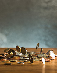 Image showing The silver and golden coins and falling coins on wooden background