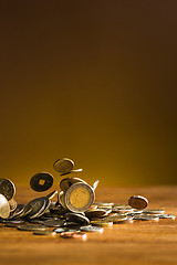 Image showing The silver and golden coins and falling coins on wooden background