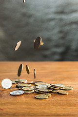 Image showing The silver and golden coins and falling coins on wooden background