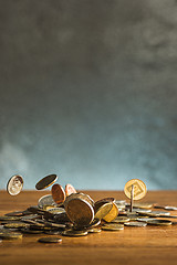 Image showing The silver and golden coins and falling coins on wooden background