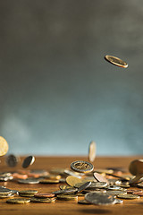 Image showing The silver and golden coins and falling coins on wooden background