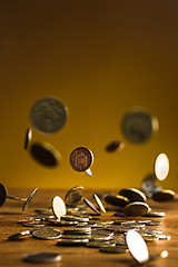 Image showing The silver and golden coins and falling coins on wooden background