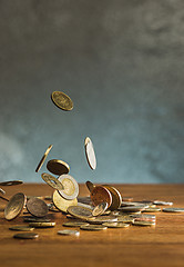 Image showing The silver and golden coins and falling coins on wooden background