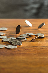 Image showing The silver and golden coins and falling coins on wooden background