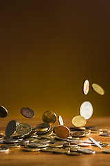 Image showing The silver and golden coins and falling coins on wooden background