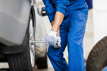 Image showing mechanic with screwdriver changing car tire