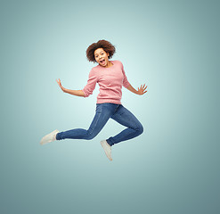 Image showing happy african american woman jumping over white