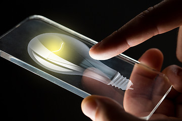 Image showing close up of hands with lightbulb smartphone