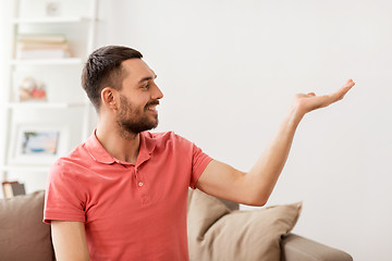 Image showing happy man holding something imaginary at home