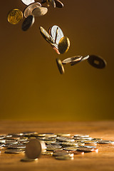 Image showing The silver and golden coins and falling coins on wooden background