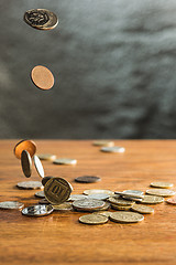 Image showing The silver and golden coins and falling coins on wooden background