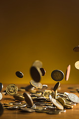 Image showing The silver and golden coins and falling coins on wooden background