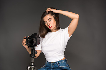 Image showing Portrait of a young woman with camera on the gray background