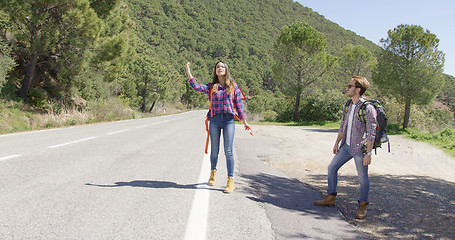 Image showing Young travellers hitch hiking on road