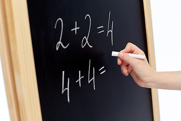 Image showing hand with chalk writing numbers on blackboard