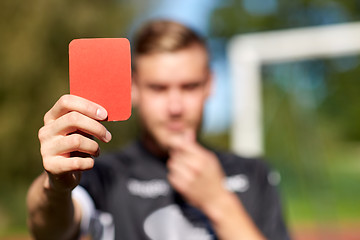 Image showing referee hands with red card on football field