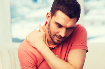 Image showing unhappy man suffering from neck pain at home
