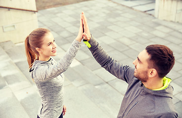 Image showing smiling couple making high five on city street