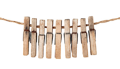 Image showing Many old wooden clothespins on a rope isolated