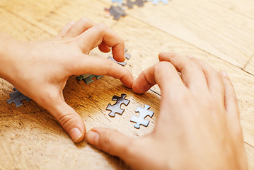 Image showing little kid playing with puzzles on wooden floor together with parent, lifestyle people concept, loving hands to each other, warm wooden interior