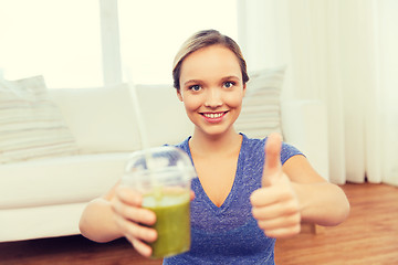 Image showing happy woman with cup of smoothie showing thumbs up