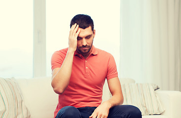 Image showing unhappy man suffering from headache at home