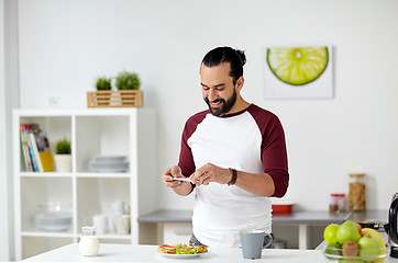 Image showing man photographing food by smartphone at home