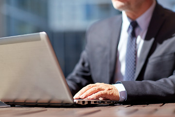 Image showing senior businessman with laptop at outdoor cafe