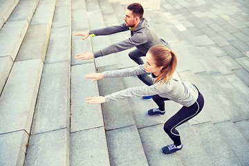 Image showing couple doing squats on city street stairs